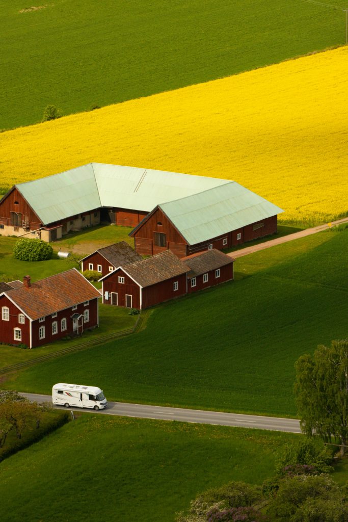 A picturesque aerial view of a farm in Gränna, Sweden with vibrant fields and red barns.